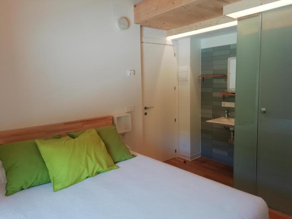 een slaapkamer met een bed met groene kussens en een badkamer bij Hotel Rural Aguazul in Covanera