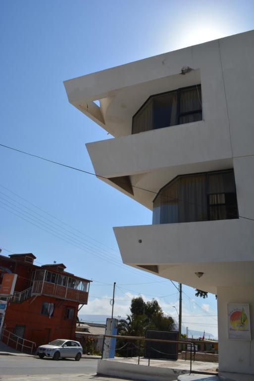 un edificio blanco con un coche aparcado delante de él en Hotel Blanco Encalada, en Bahía Inglesa