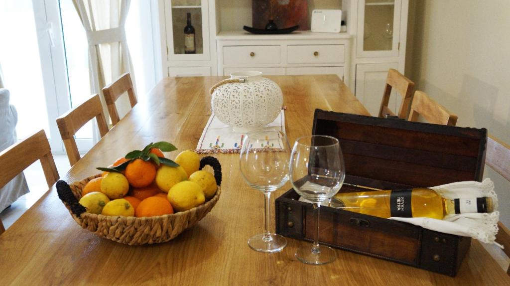 - une table en bois avec une corbeille de fruits et des verres à vin dans l'établissement Michaela, à Gázion