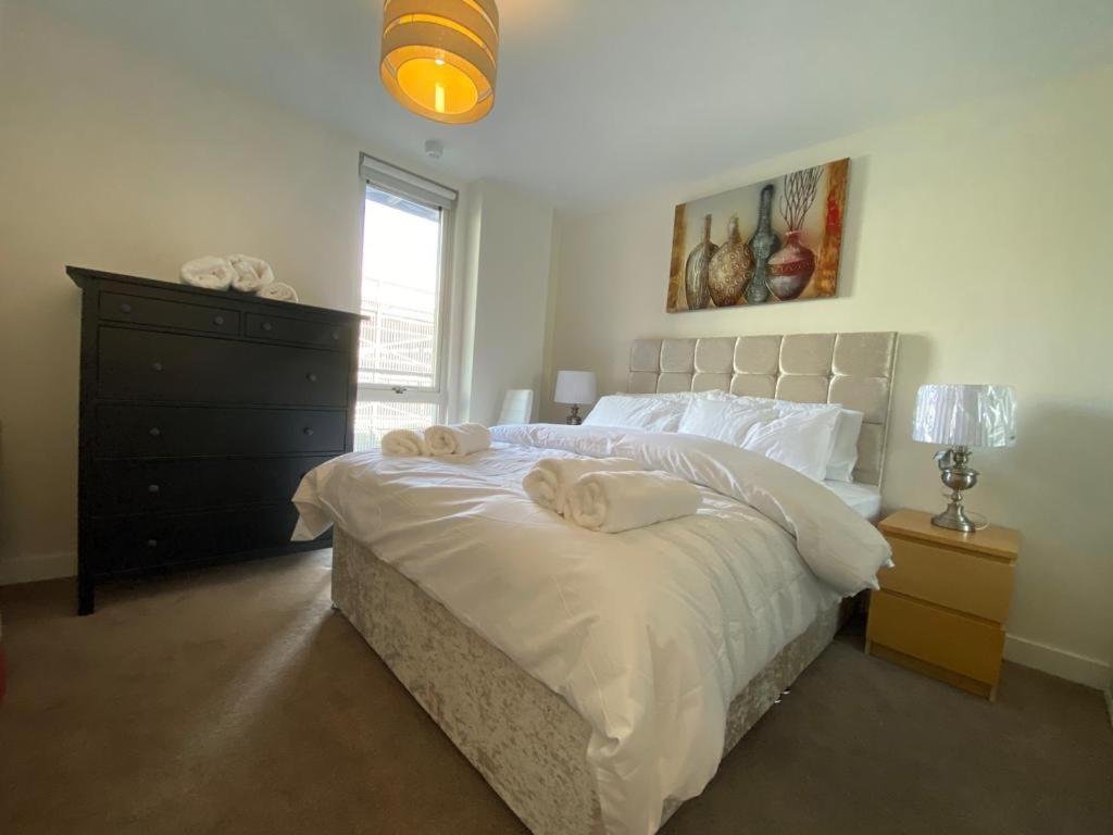 a bedroom with a large bed with two towels on it at Central Milton Keynes hub one bedroom secured apartment in Milton Keynes