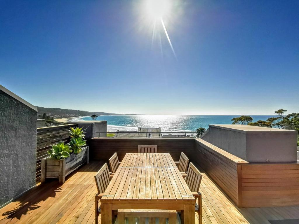 une terrasse en bois avec une table et la plage dans l'établissement Lorne Beachfront Accommodation, à Lorne