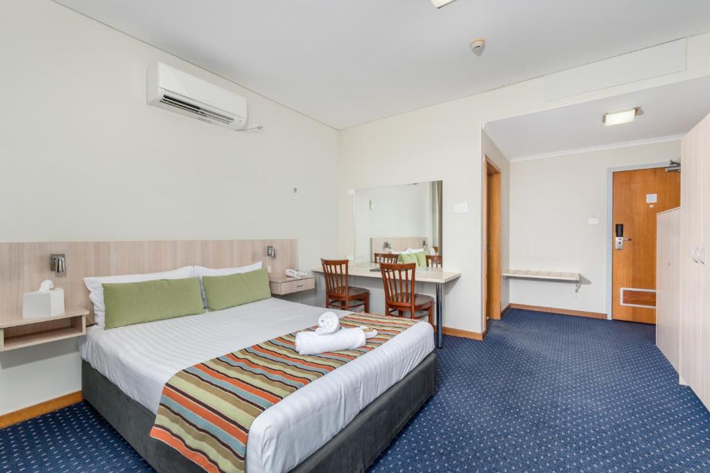 une chambre d'hôtel avec un lit, une table et des chaises dans l'établissement Tudor Inn Newcastle, à Newcastle