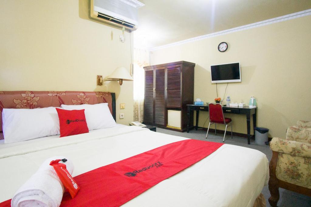 a bedroom with a large bed with a red blanket at RedDoorz plus near Pelabuhan Bitung in Bitung