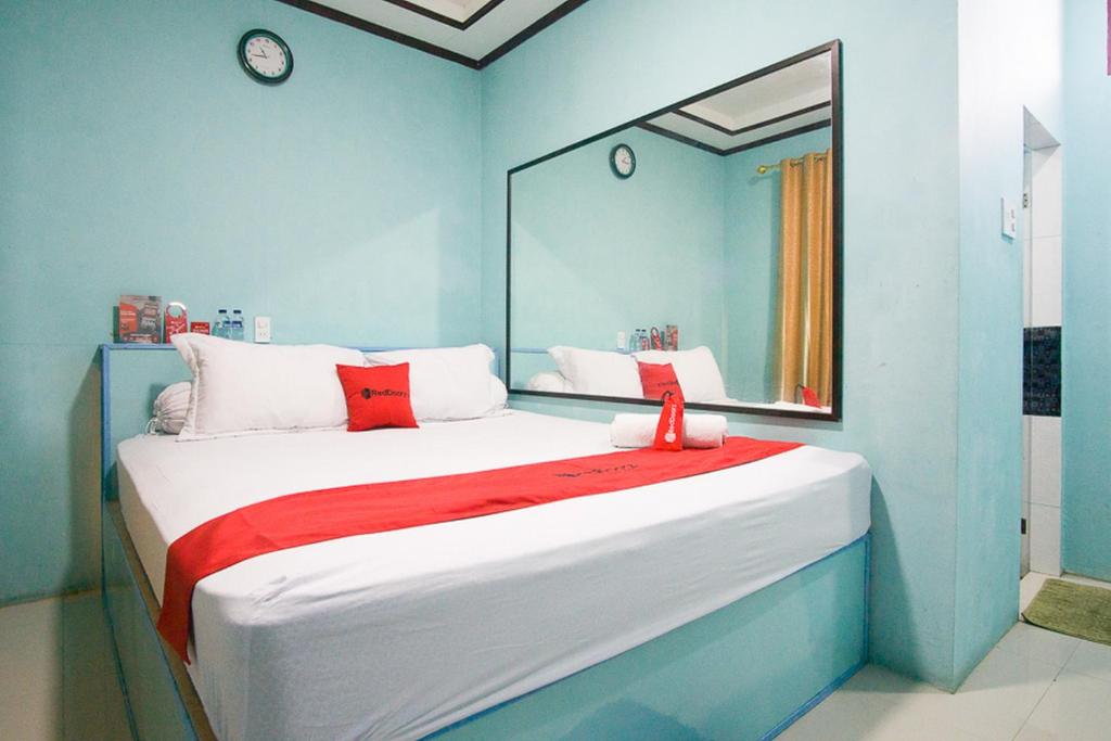 um quarto com uma cama grande e um espelho em RedDoorz near Mikie Holiday Funland Berastagi em Berastagi