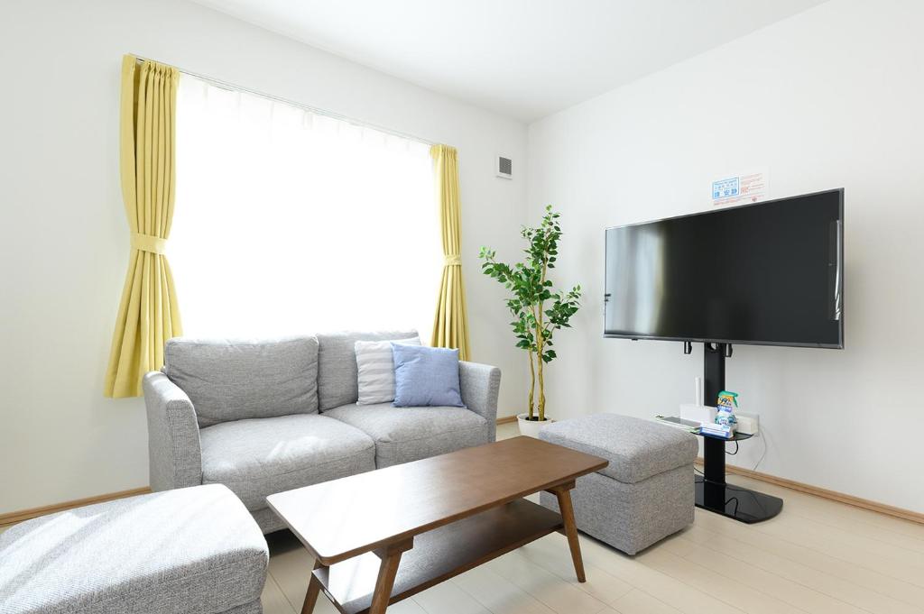 - un salon avec un canapé et une télévision dans l'établissement SAKURA93, à Sapporo
