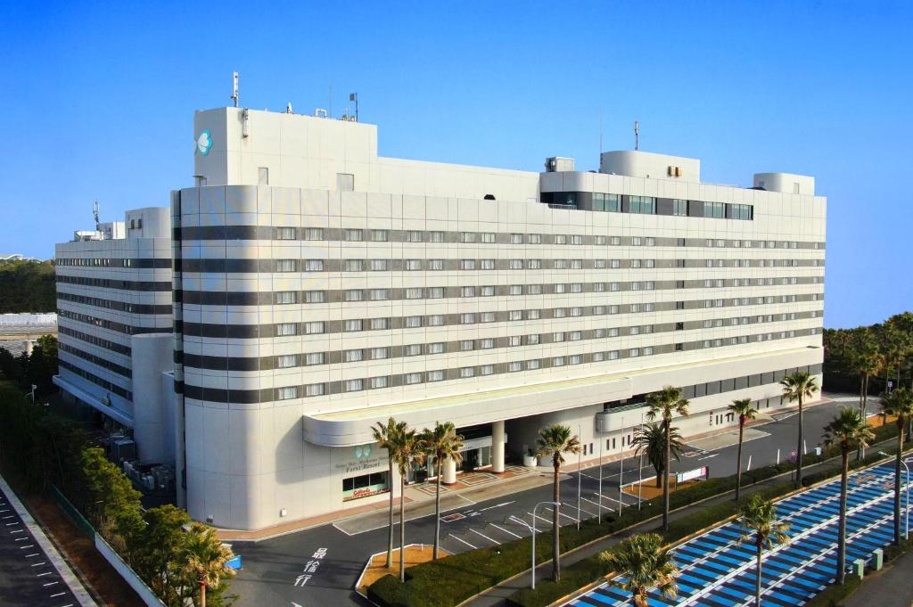 a large white building with palm trees in front of it at Tokyo Bay Maihama Hotel First Resort in Urayasu