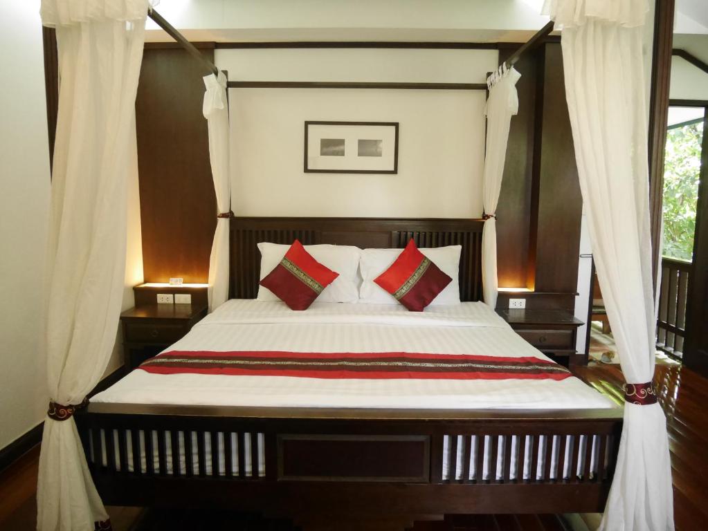 Schlafzimmer mit einem Bett mit roten und grünen Kissen in der Unterkunft Ping Phu Place in Chiang Mai