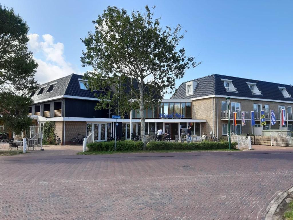 un grand bâtiment avec drapeaux devant lui dans l'établissement Hotel Nes, à Nes