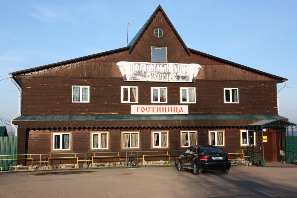 un bâtiment avec une voiture garée devant lui dans l'établissement Tourist Complex Botik, à Pereslavl-Zalesski