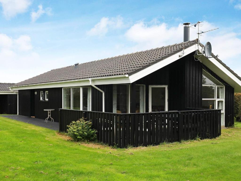 una casa negra con una valla delante en 8 person holiday home in Hj rring, en Hjørring