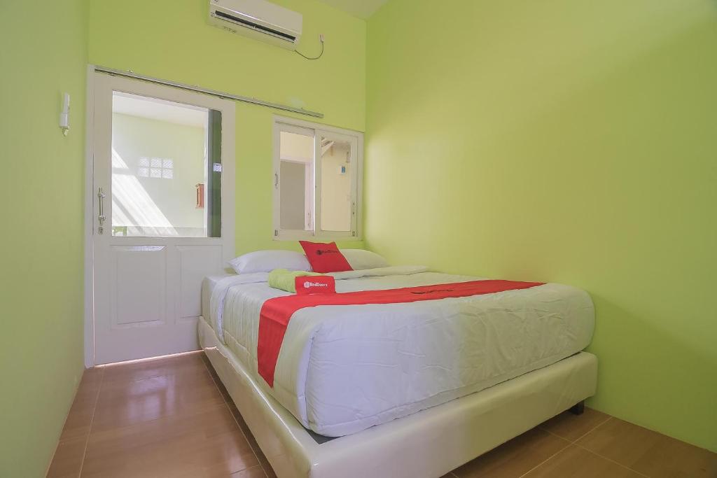 een kleine slaapkamer met een bed en een deur bij RedDoorz Syariah near Museum Wisma Karya Subang in Subang