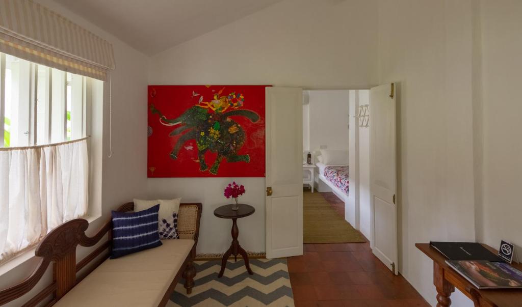 a living room with a couch and a painting on the wall at Nyne Hotels Rock Villa, Bentota in Bentota