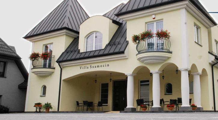 un edificio blanco con 2 balcones y flores. en Villa Szamocin, en Varsovia