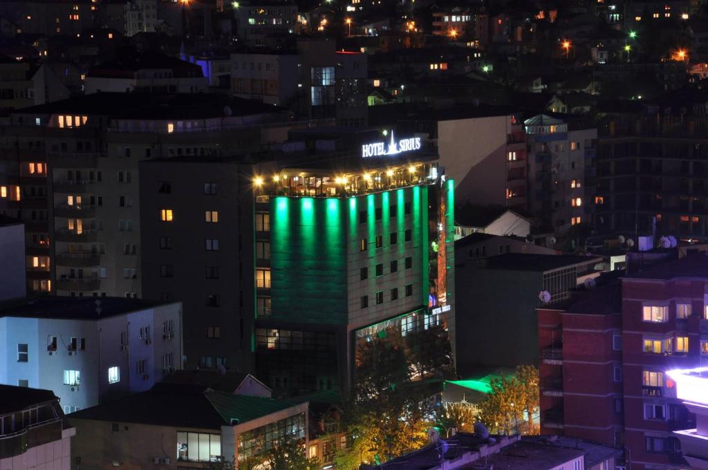 un edificio alto con luces verdes por la noche en Hotel Sirius en Pristina