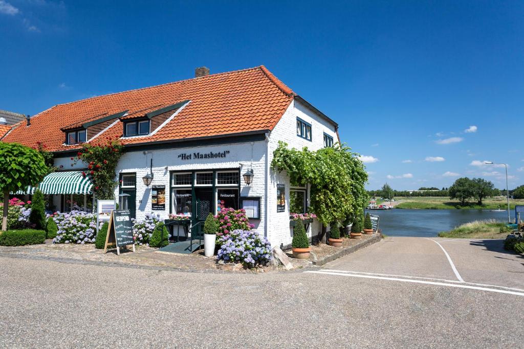 un edificio blanco con flores en un estacionamiento en Het Maashotel, en Broekhuizen