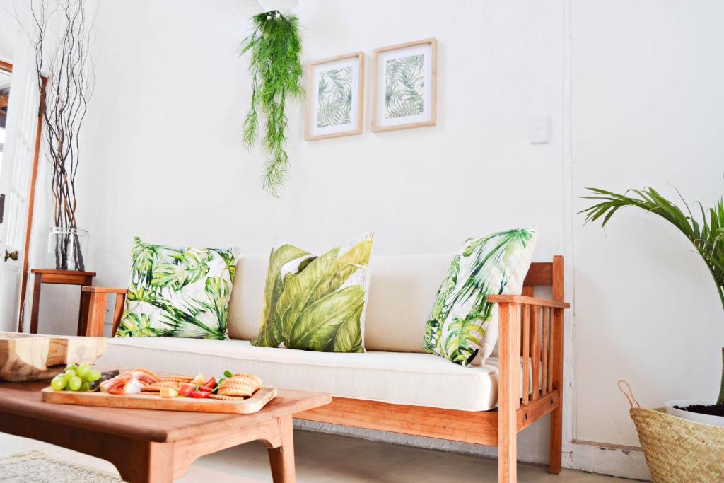 a living room with a white couch with tropical pillows at The Greenery in Velddrif