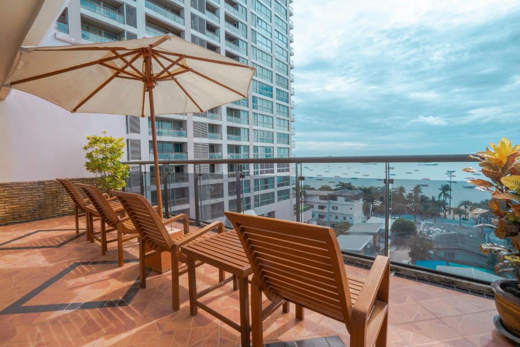 a patio with chairs and an umbrella on a balcony at Mike Beach Resort in Pattaya