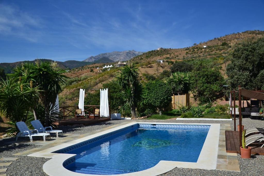 una piscina in un cortile con montagne sullo sfondo di The African House a Tolox