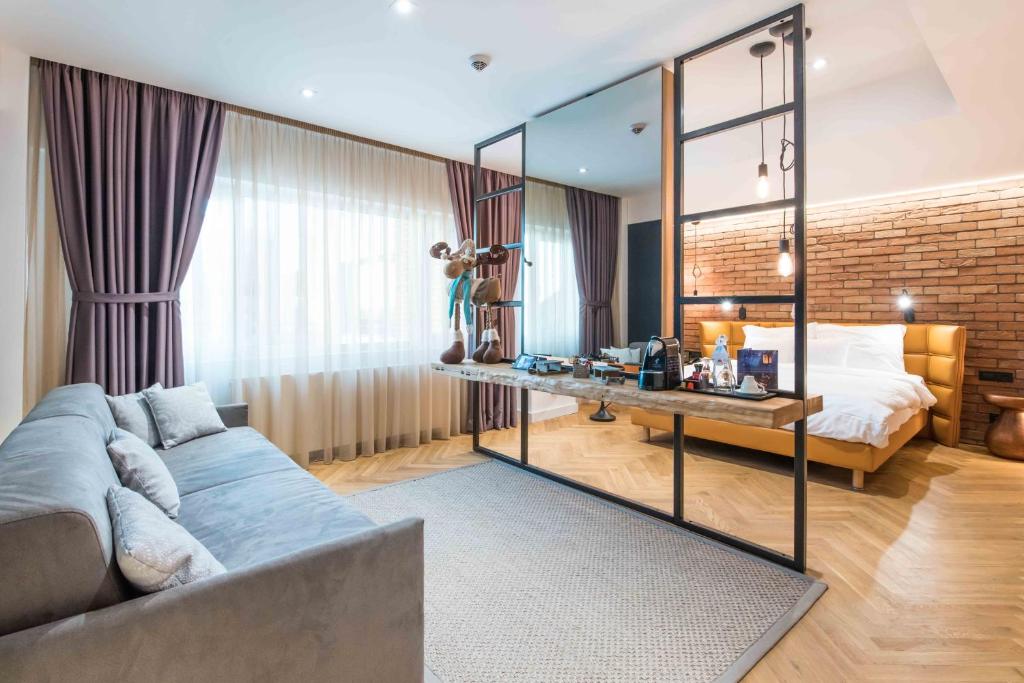 a room with a couch and a bed and a mirror at Caro Hotel in Bucharest