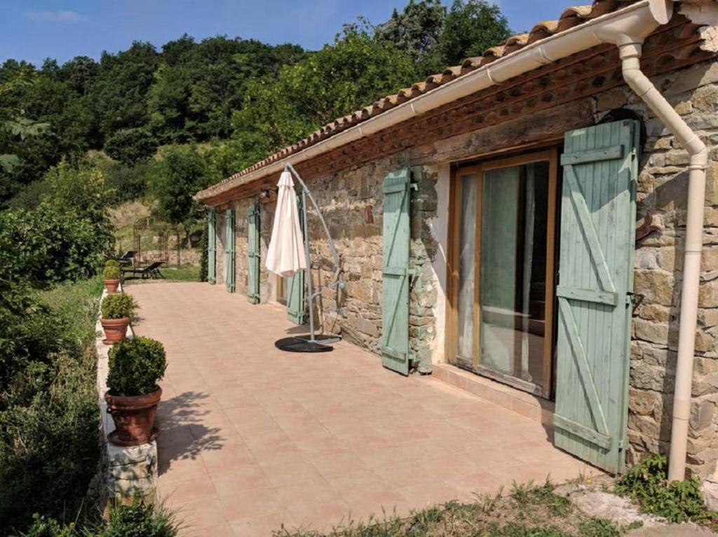 un edificio de piedra con patio y sombrilla en Le Belvedere, en Lairière