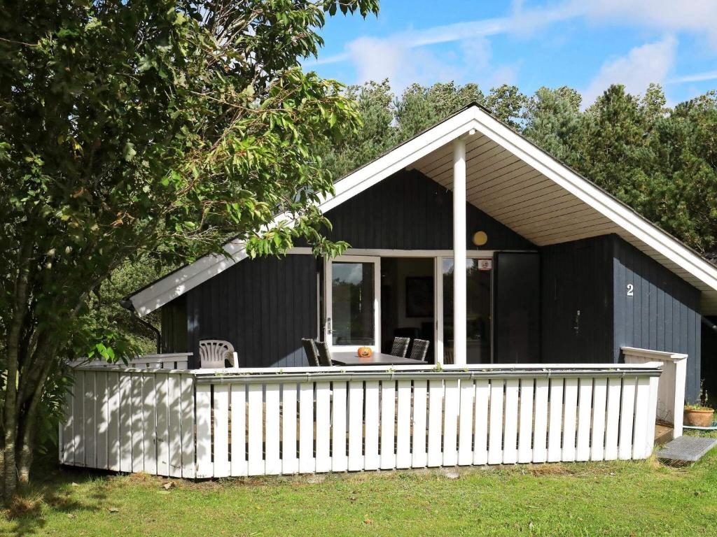 ein schwarzes Cottage mit einem weißen Zaun in der Unterkunft 6 person holiday home in Vemb in Vemb