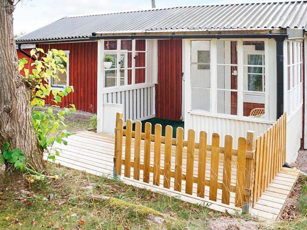 a red and white tiny house with a wooden fence at 3 person holiday home in OSKARSHAMN in Oskarshamn