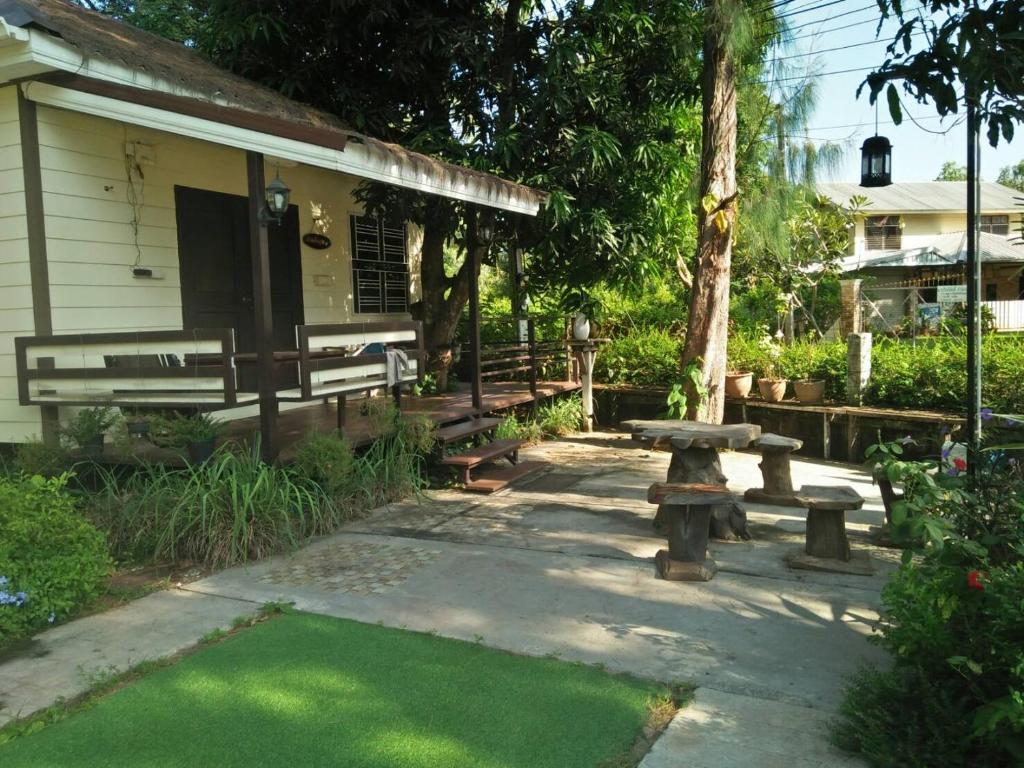 a patio with benches and a picnic table in front of a house at Wasuthan Garden House in Nong Khai