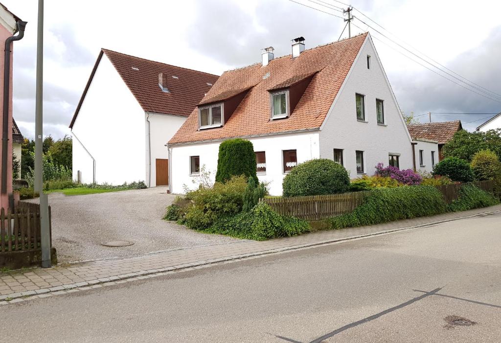 ein weißes Haus mit rotem Dach auf einer Straße in der Unterkunft Kleines Häuschen im Grünen in Monheim