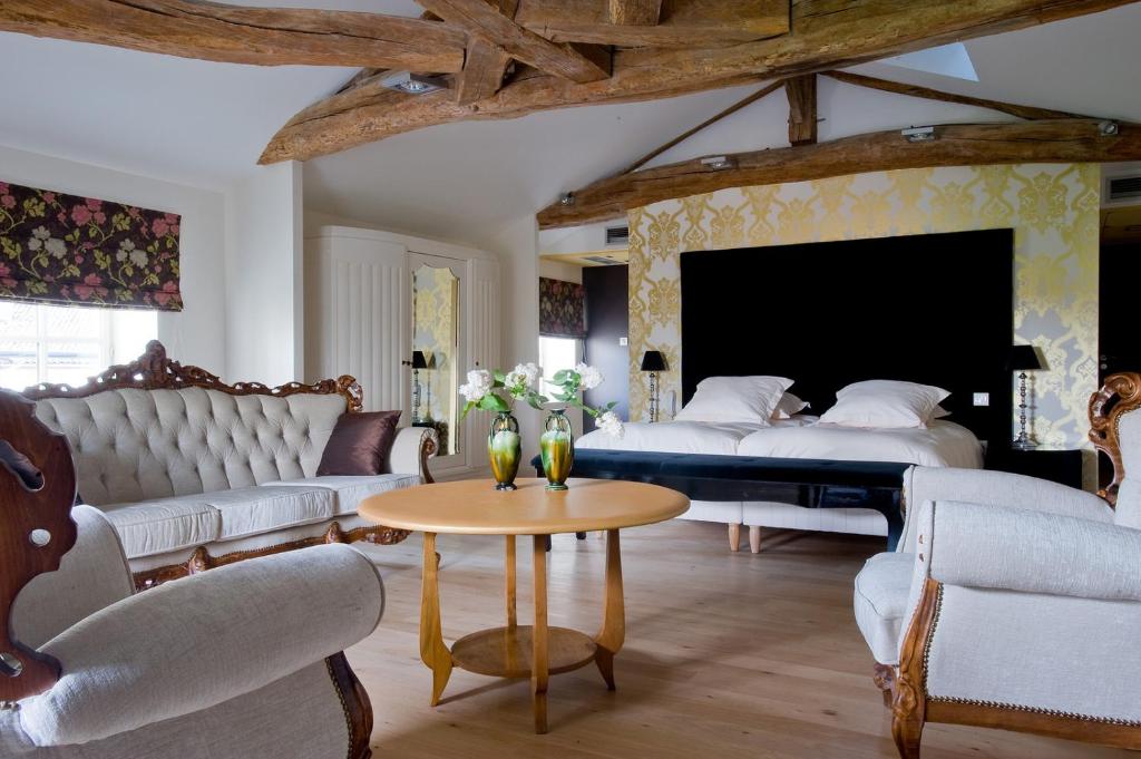 a bedroom with a bed and a table and chairs at Frédéric Carrion Hôtel et Spa in Viré
