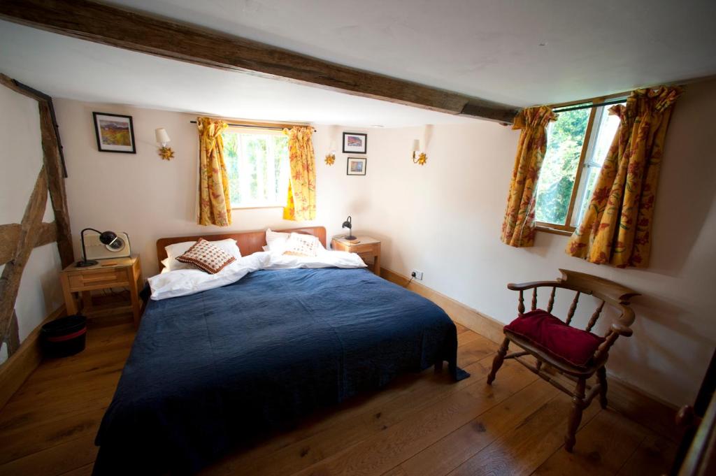 a bedroom with a blue bed and a chair at Wyre Forest Cottage in Bewdley