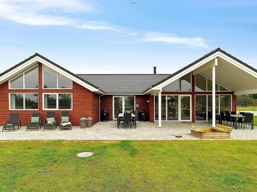une maison en briques rouges avec des chaises et une terrasse dans l'établissement 18 person holiday home in Grenaa, à Grenå