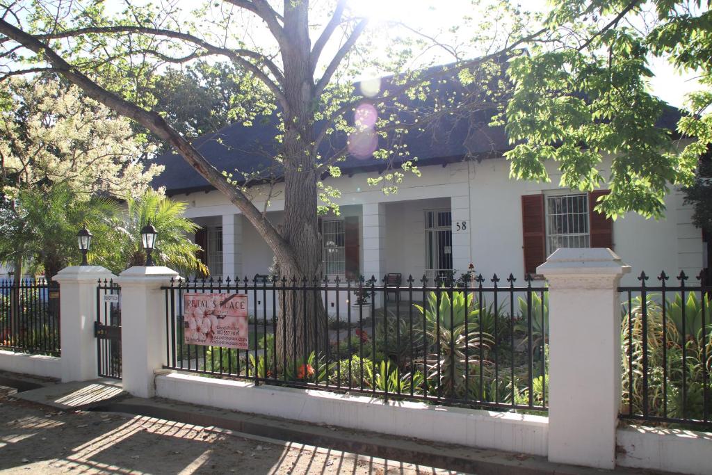 a white house with a black fence and a tree at Petal's Place in Robertson