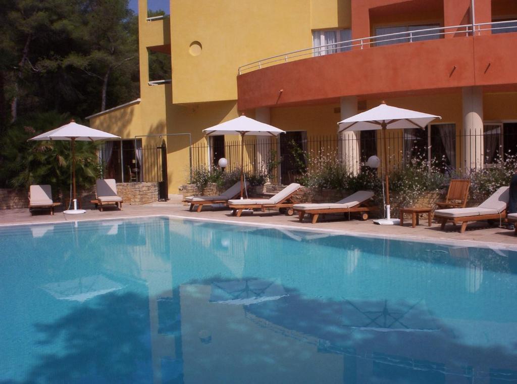 a swimming pool with chairs and umbrellas next to a building at Hôtel Omega in Valbonne