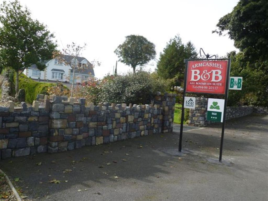 una señal frente a una pared de retención de piedra en Armcashel B&B en Castlerea