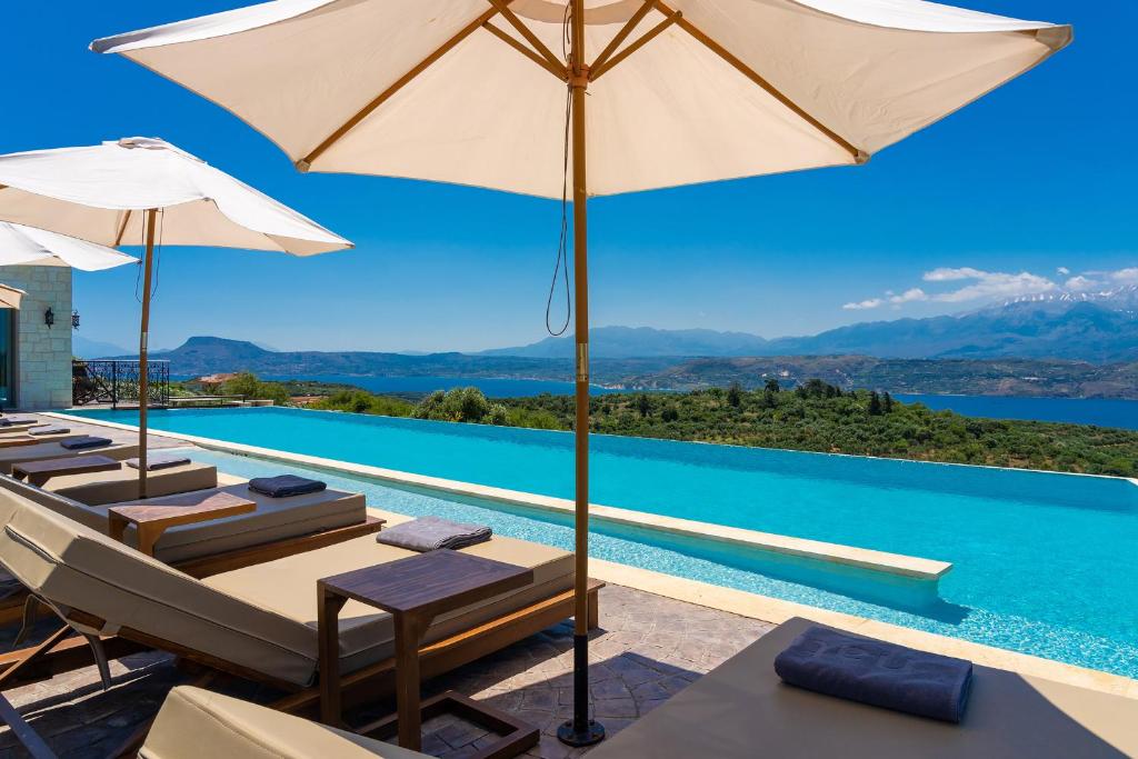 a pool with chairs and umbrellas next to a swimming pool at Elements Villa in Galangádhos