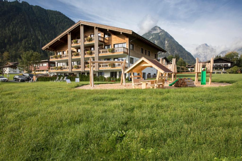 a large house in a field with mountains in the background at Wagner's Aparthotel in Pertisau