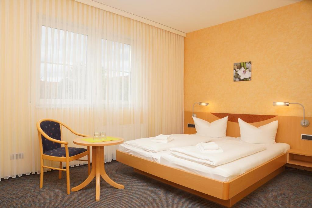 a bedroom with a bed and a table and a chair at Warias Hotel & Restaurant am Geiseltalsee - Nähe Merseburg in Braunsbedra