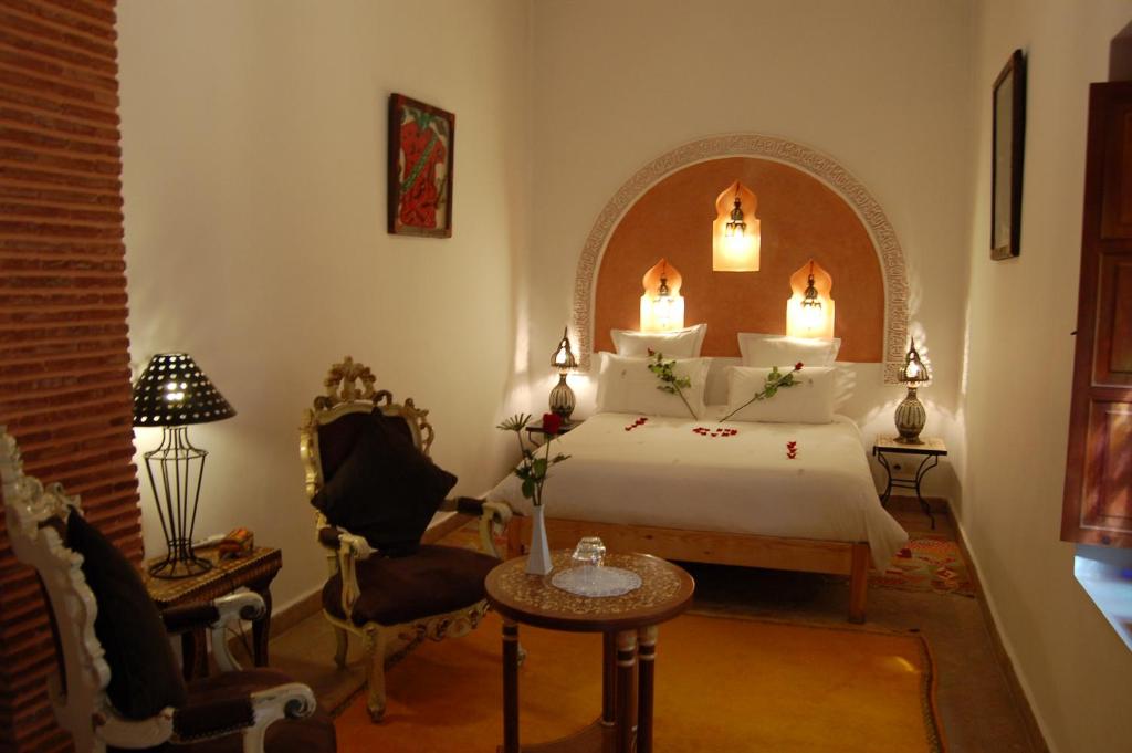 um quarto com uma cama, uma mesa e uma cadeira em Riad Les Trois Palmiers El Bacha em Marrakech