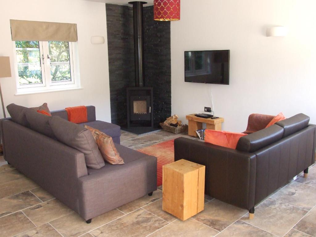 een woonkamer met 2 banken en een televisie bij Stable Cottage in Redlynch