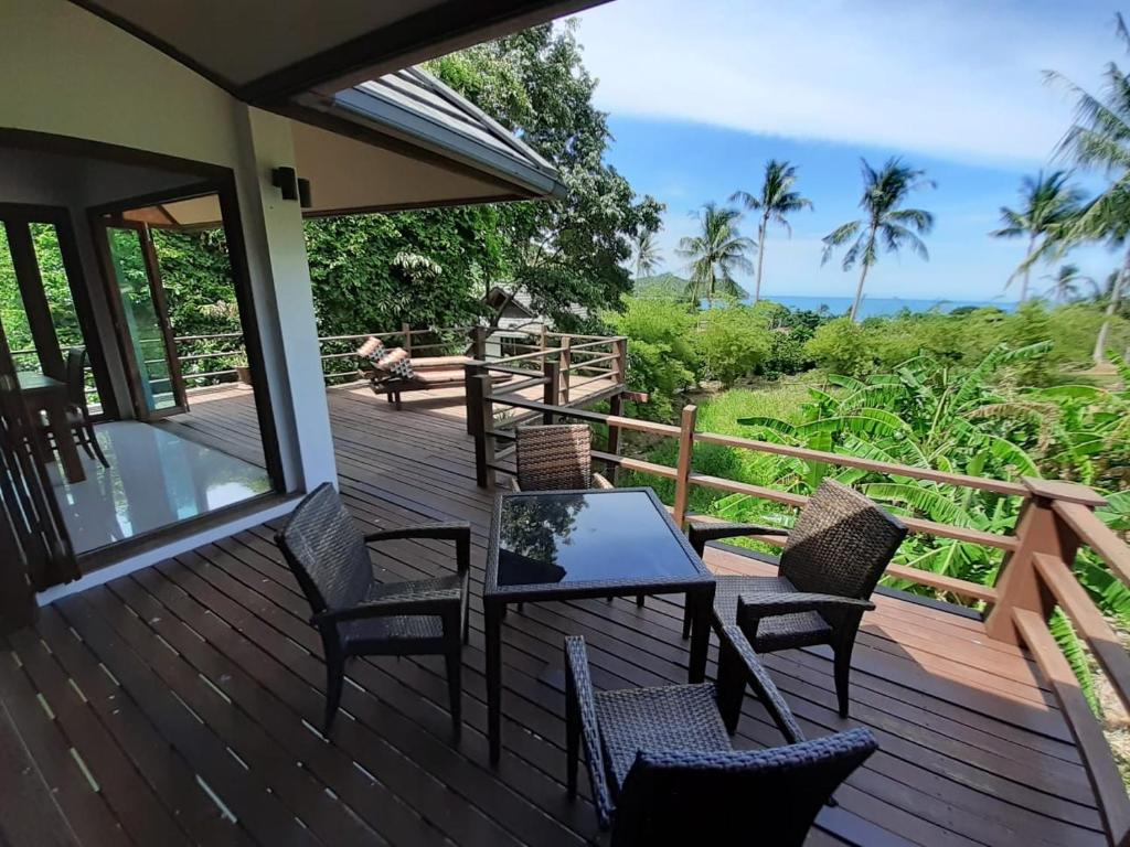 una terraza con mesa, sillas y el océano en Sea View Villa, en Thong Nai Pan Yai