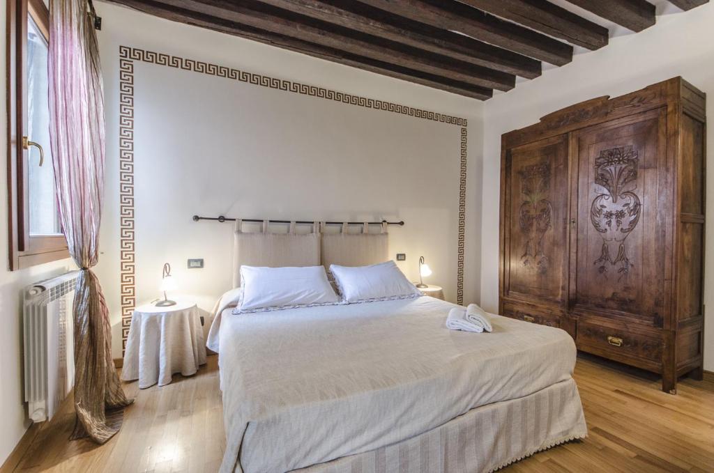 ヴェネツィアにあるResidenza Dondelの大きなベッドと木製の壁が備わるベッドルーム1室が備わります。