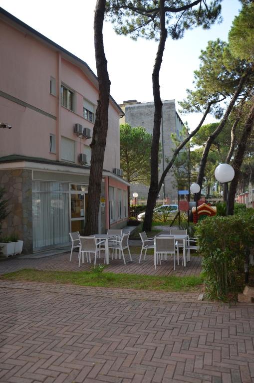 um grupo de mesas e cadeiras ao lado de um edifício em Garnì Garten em Milano Marittima