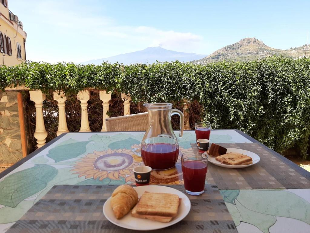 uma mesa com dois pratos de pão e um jarro de sumo em Le nuove porte di Taormina em Taormina