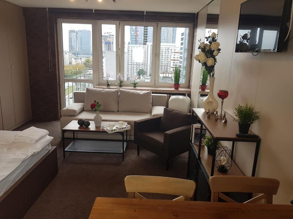 uma sala de estar com um sofá e uma mesa em Alma Apartments Rondo ONZ em Varsóvia
