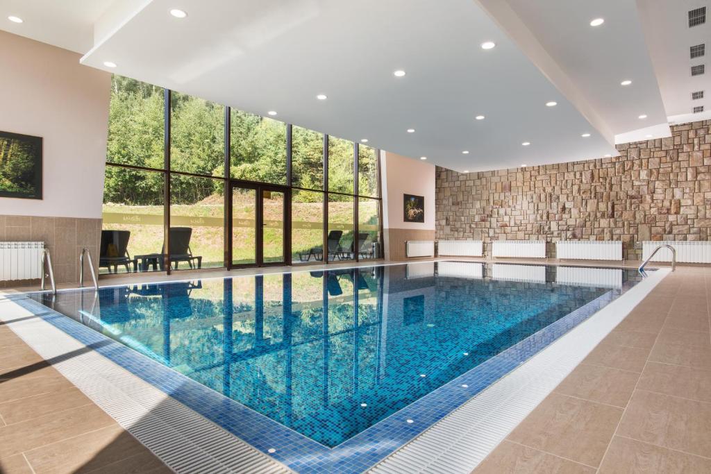 une grande piscine avec un grand mur de fenêtres dans l'établissement Hotel Villa Magus, à Kladnitsa