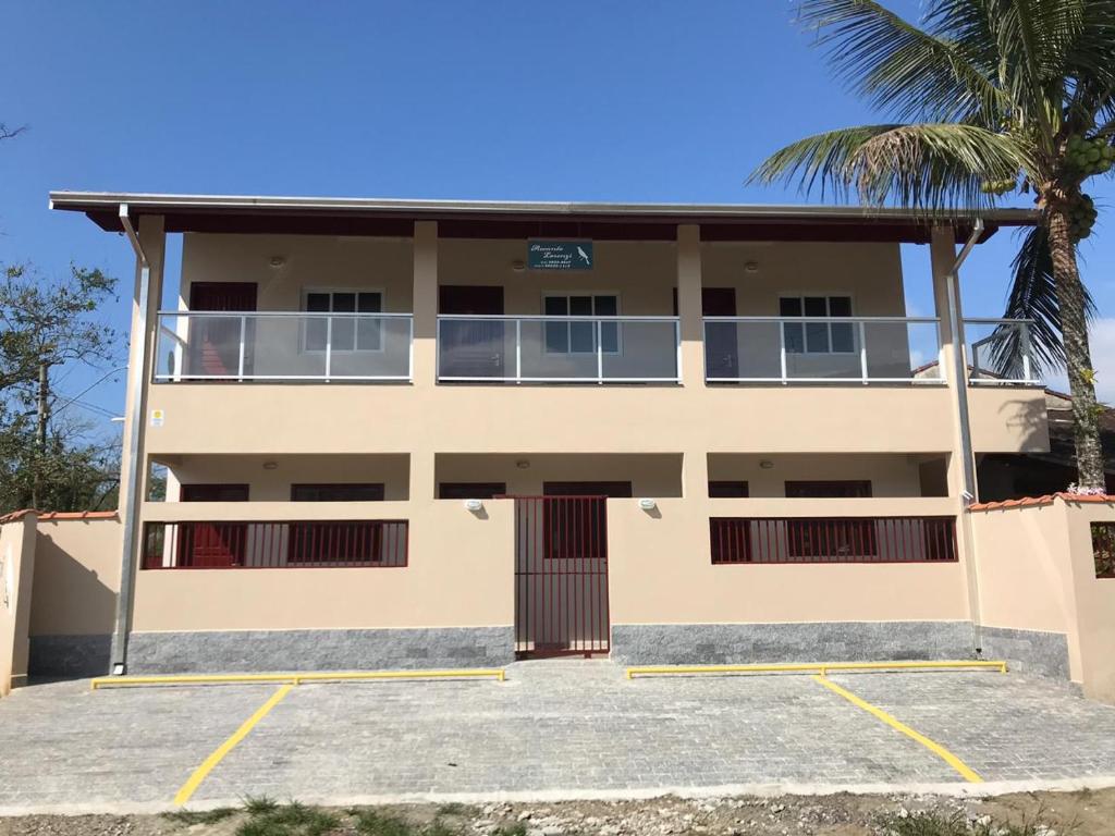 a building with a palm tree in front of it at Recanto Lorenzi - Apartamentos in Ubatuba