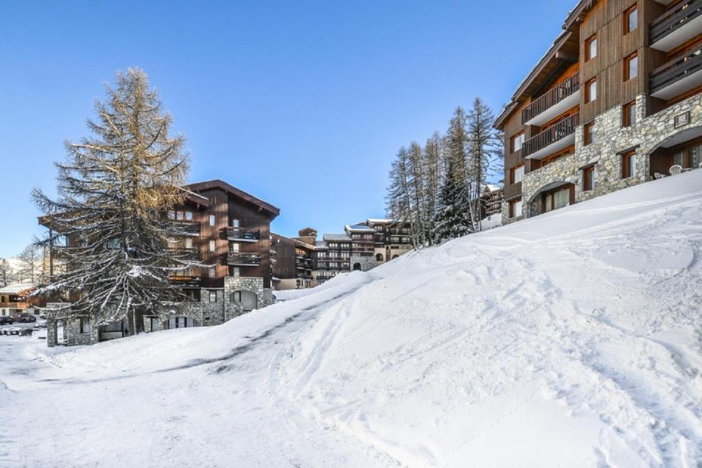 a snow covered ski slope in front of a building at Residence Le Hameau du Sauget - maeva Home in Les Coches