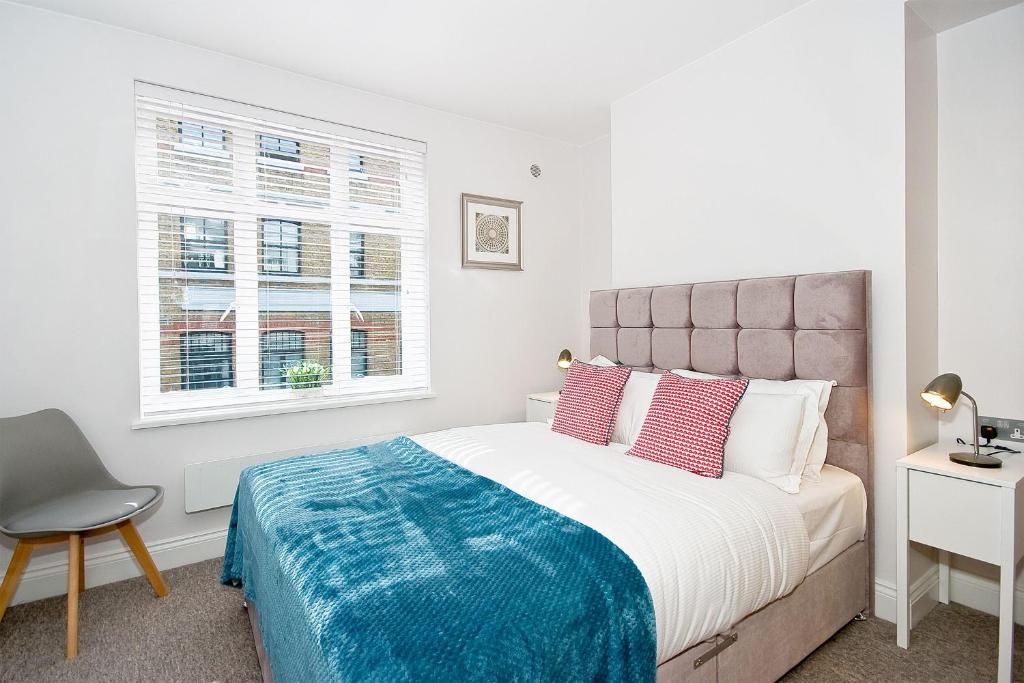 een slaapkamer met een bed, een stoel en een raam bij F4 Greek Street by City Living London in Londen