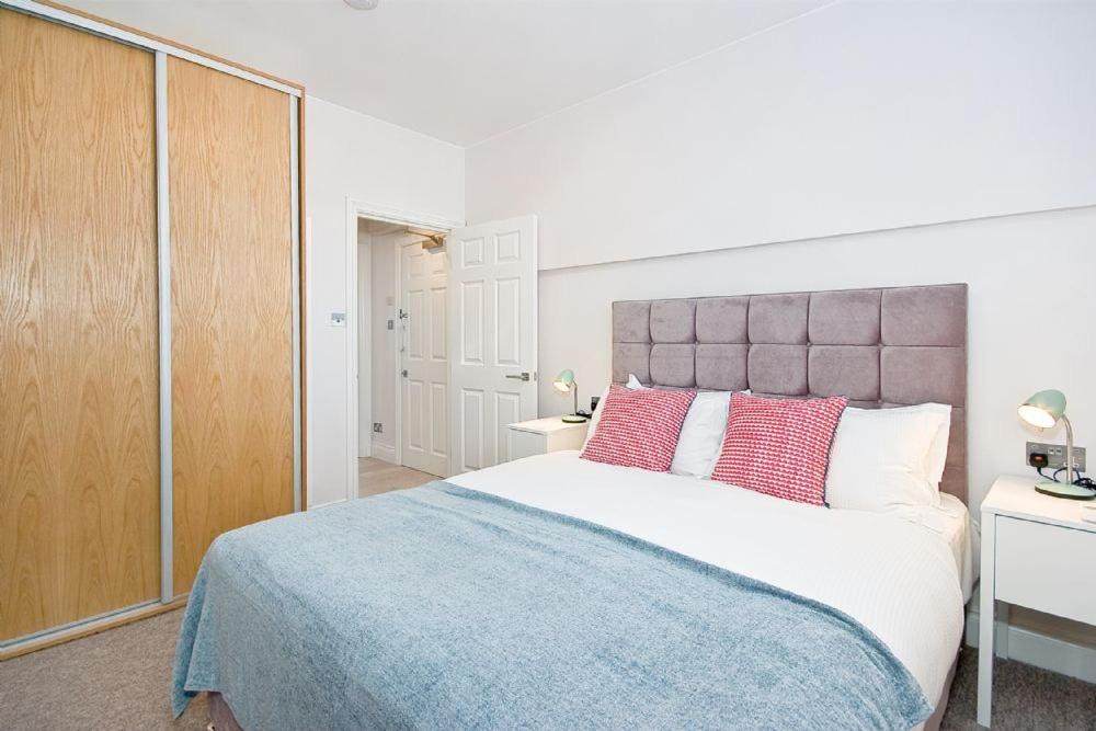 a bedroom with a large bed with red pillows at F1 Greek Street by City Living London in London