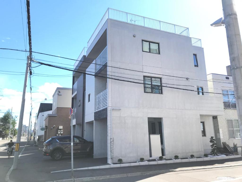 札幌的住宿－Arts Candy Sapporo-Villa Nakajima，前面有一辆汽车停放的白色建筑